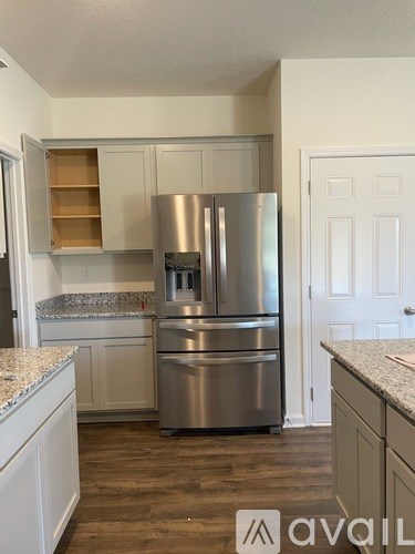 A kitchen with a stainless steel refrigerator and cabinets.