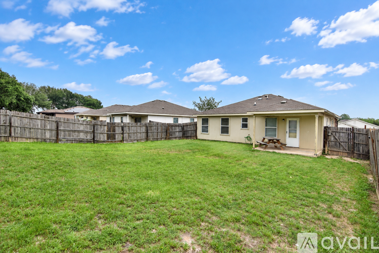 A grassy backyard with a house and a fence.