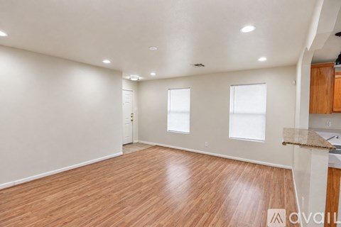 A hallway with wood flooring and a door leading to a balcony.