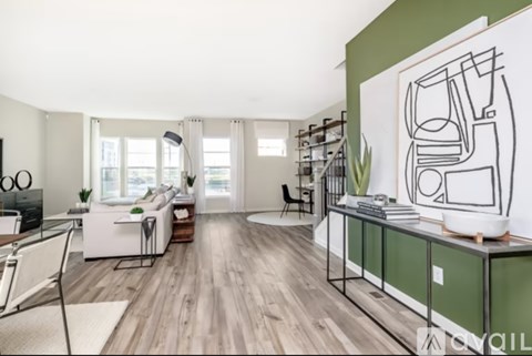 A modern living room with a white sofa and a green accent wall.