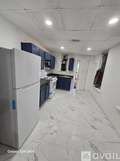 A kitchen with a white refrigerator and marble flooring.