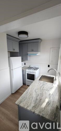 A kitchen with a marble countertop and a white refrigerator.