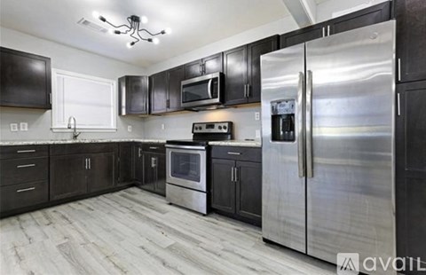A modern kitchen with stainless steel appliances and wooden flooring.