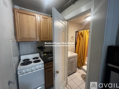 A kitchen with a stove top oven and wooden cabinets.