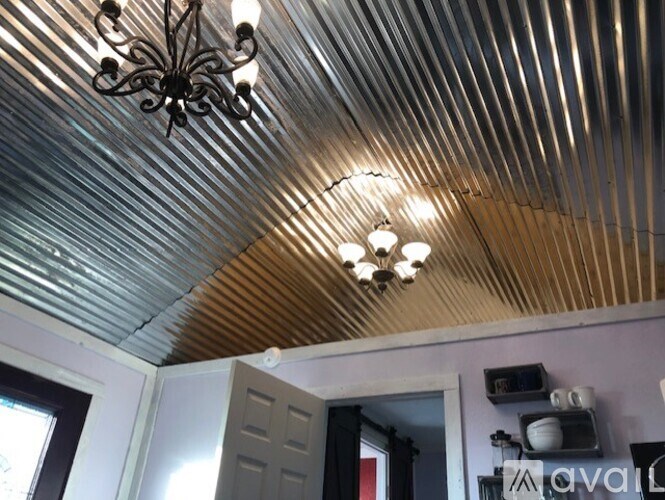A chandelier hangs from a corrugated metal ceiling.