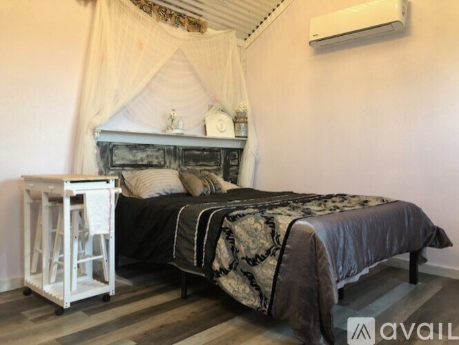 A bedroom with a bed, nightstand, and a window with curtains.