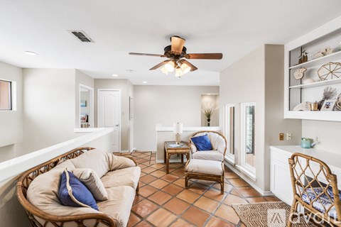 A living room with a tan couch and a ceiling fan.