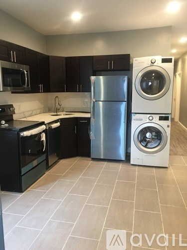A kitchen with a stainless steel refrigerator and washing machine.