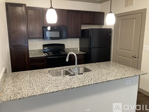 A kitchen with a granite countertop and a black refrigerator.