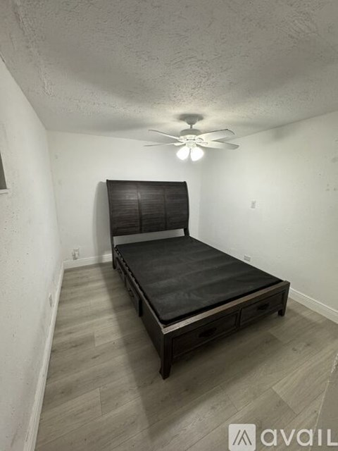 A bedroom with a bed, wooden floor, and a ceiling fan.