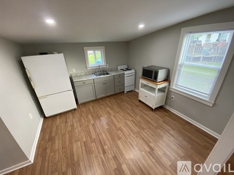 A kitchen area with wooden flooring and white appliances.
