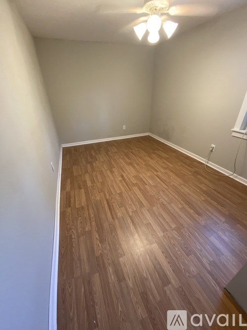 A room with wooden flooring and a ceiling fan.