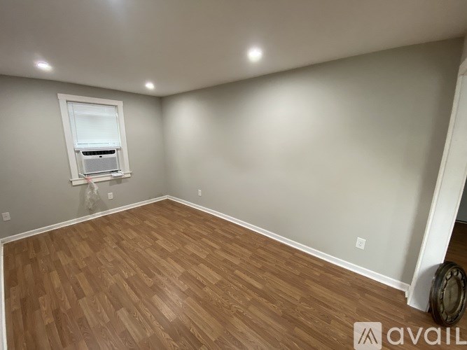 A room with wooden flooring and a window with blinds.