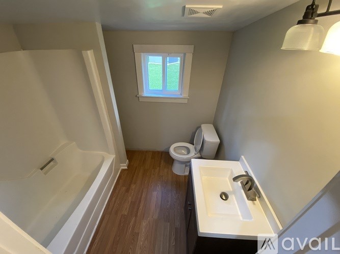 A small bathroom with a toilet, sink, and a window.