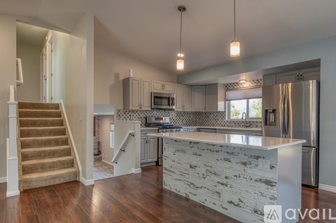 A kitchen with a white counter top and a staircase with a beige carpet.