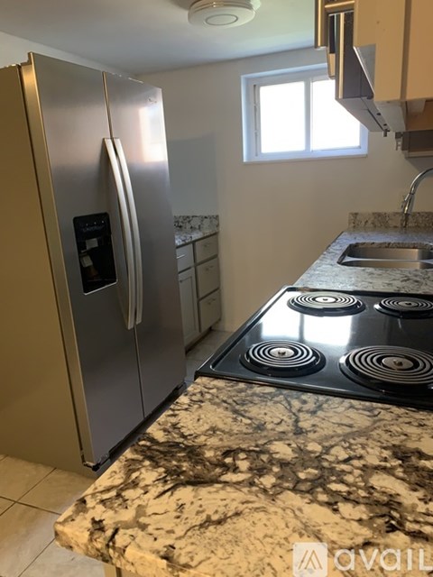 A kitchen with a stainless steel refrigerator and a granite countertop.