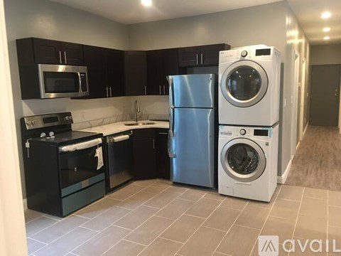 A modern kitchen with a stainless steel refrigerator and washing machine.