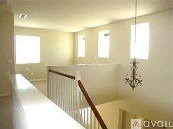 A chandelier hangs in a well-lit room with a staircase.