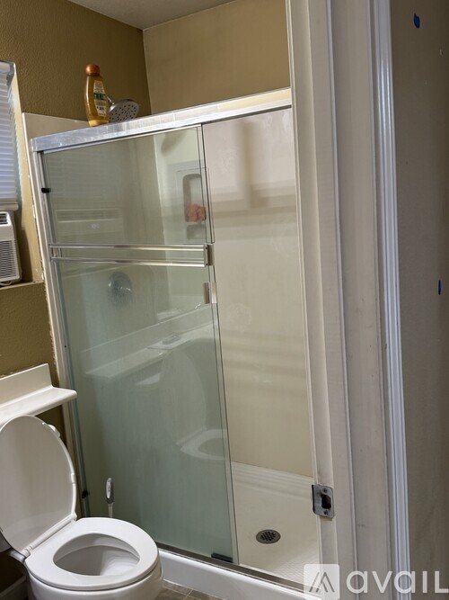 A white toilet is in a bathroom with a walk-in shower.
