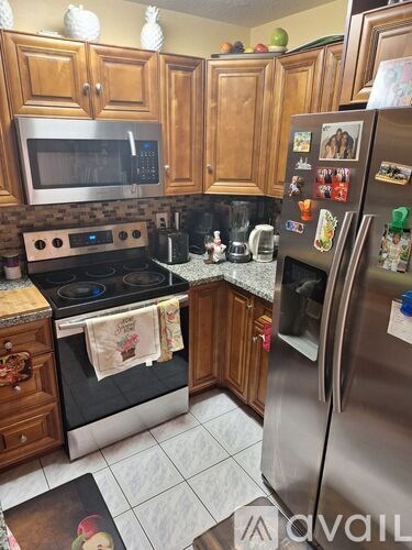 A kitchen with wooden cabinets and a stainless steel refrigerator.