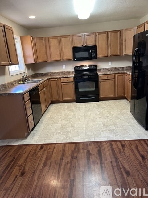A kitchen with wooden cabinets and black appliances.