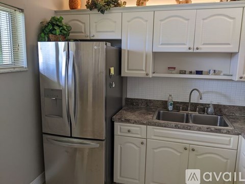 A kitchen with a stainless steel refrigerator and white cabinets.