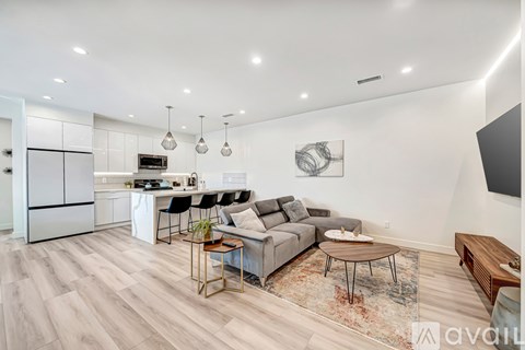 A modern kitchen and living room with a grey sofa and wooden coffee table.
