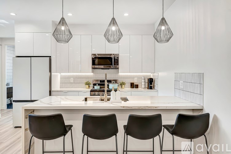 A modern kitchen with a white island and black chairs.