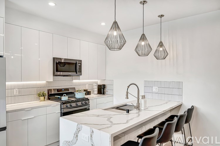 A modern kitchen with a white countertop and black chairs.
