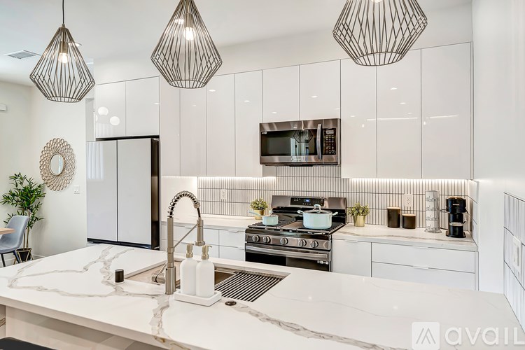 A modern kitchen with a marble countertop and stainless steel appliances.