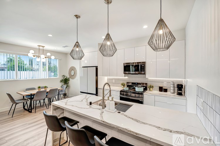 A modern kitchen with a large island and pendant lights.