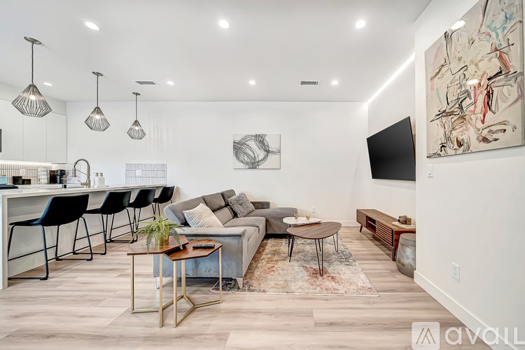 A modern living room with a grey sofa, a coffee table, and a painting on the wall.