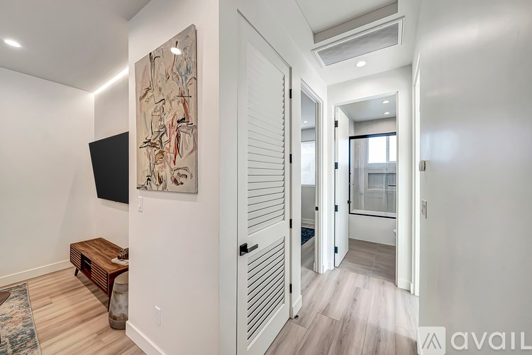 A hallway with a painting on the wall and a bench.