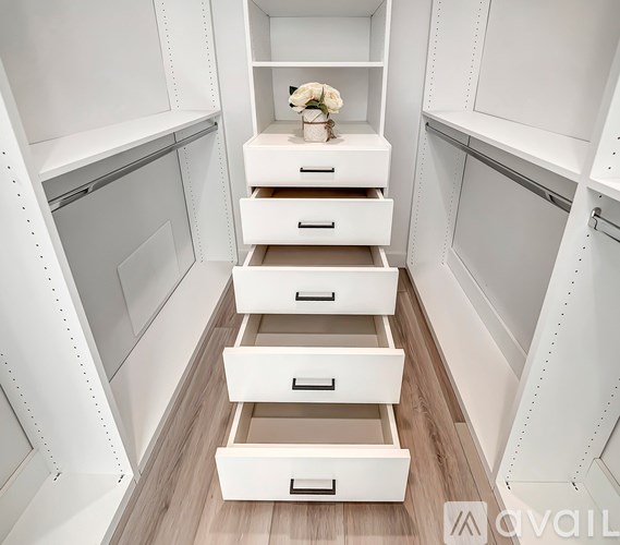 A white drawer with a black handle is in the middle of a set of white drawers.