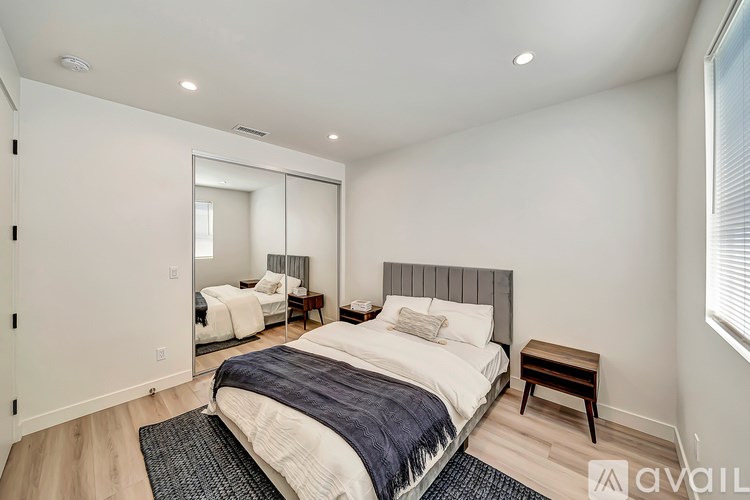 A bedroom with a bed, a chair, and a mirror.
