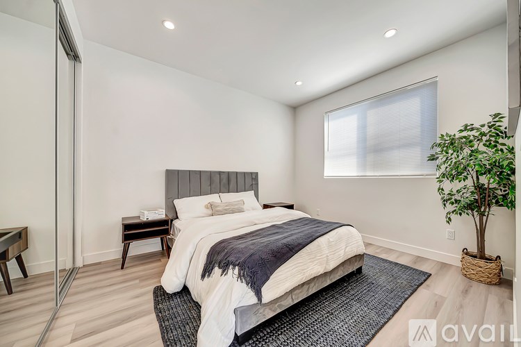 A bedroom with a large bed and a plant.