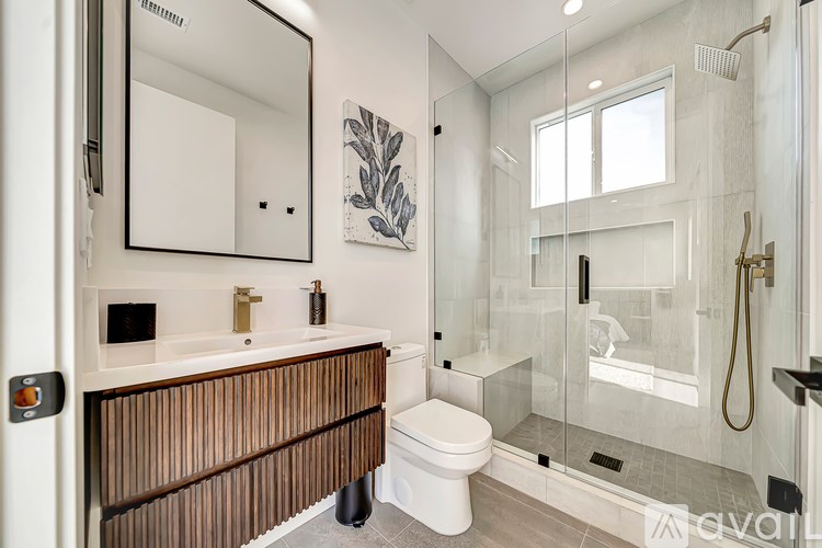 A modern bathroom with a wooden vanity and a walk-in shower.
