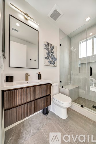 A modern bathroom with a white toilet and a large mirror.