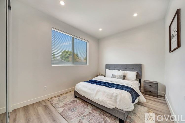 A bedroom with a large bed and a window overlooking a tree.