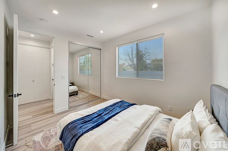 A bedroom with a large bed and a view of trees through the window.