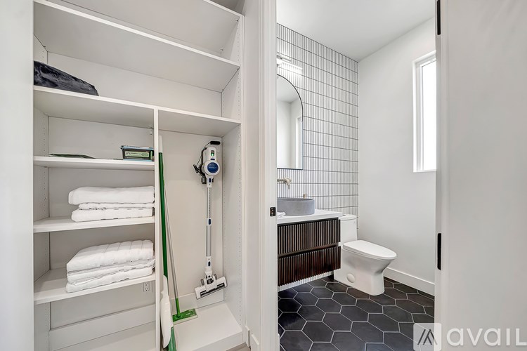 A bathroom with a toilet, sink, and towel shelf.