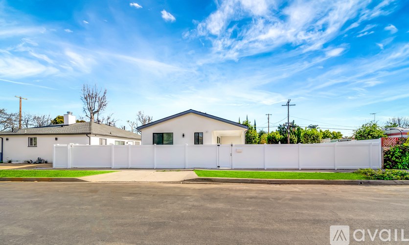 A white house with a fence in front of it is for sale.