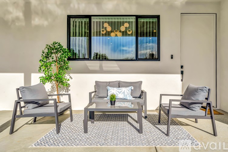 A patio with a table, chairs and a potted plant.