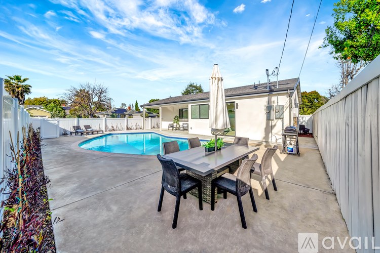 A backyard with a table and chairs and a pool.