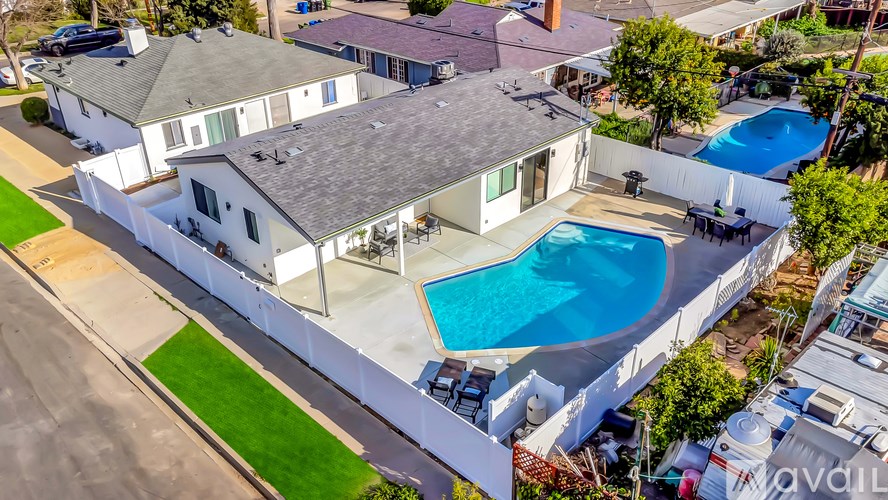 A white house with a blue pool in the backyard.