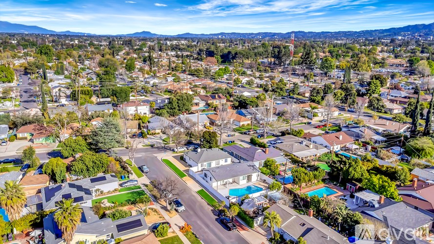 A bird's eye view of a residential neighborhood with houses, trees, and a clear sky.