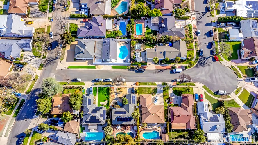 A bird's eye view of a residential area with houses and swimming pools.