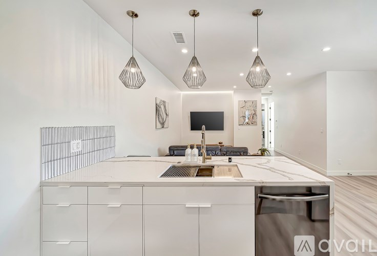 A modern kitchen with a white countertop and cabinets, a black dishwasher, and a white backsplash.