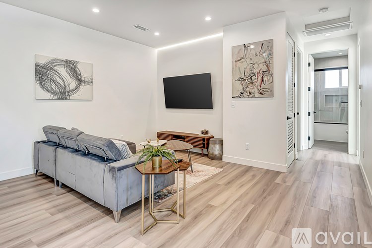 A living room with a grey couch, a coffee table, and a painting on the wall.
