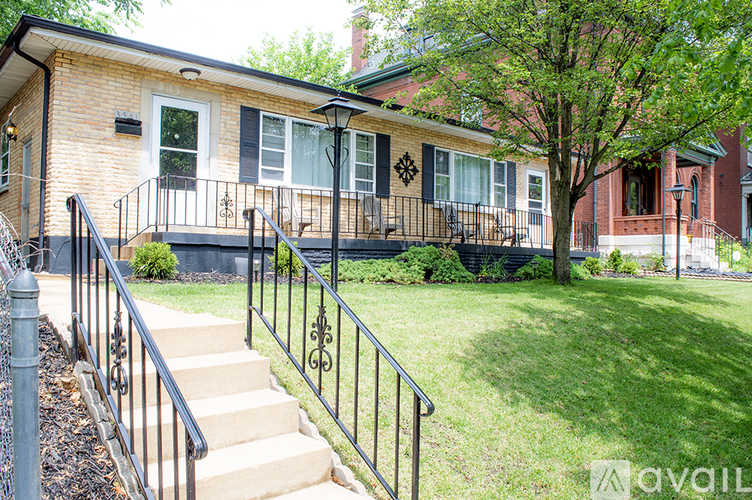A house with a black railing and steps leading to the front door.